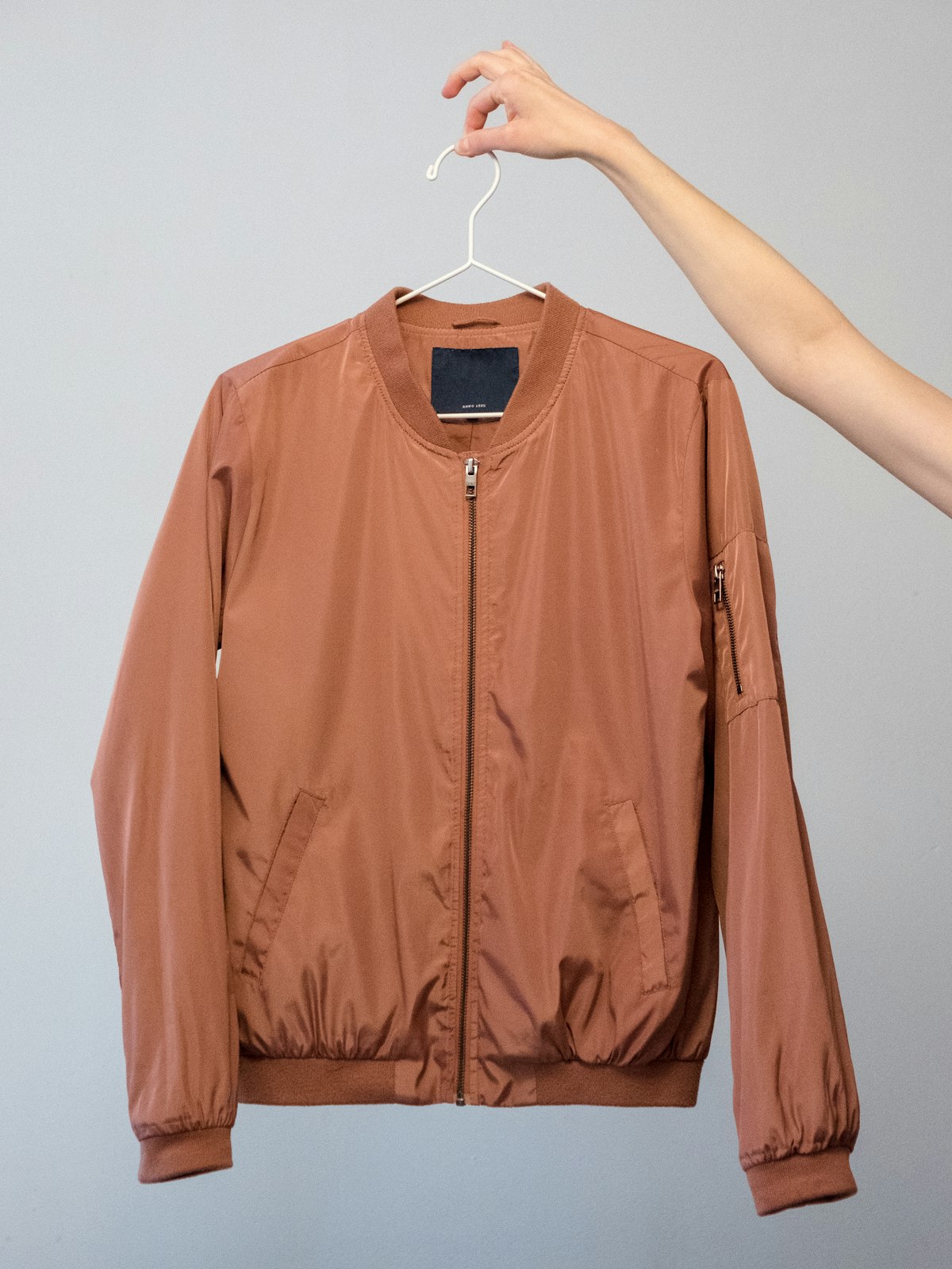 Rust-coloured bomber jacket held up on a hanger