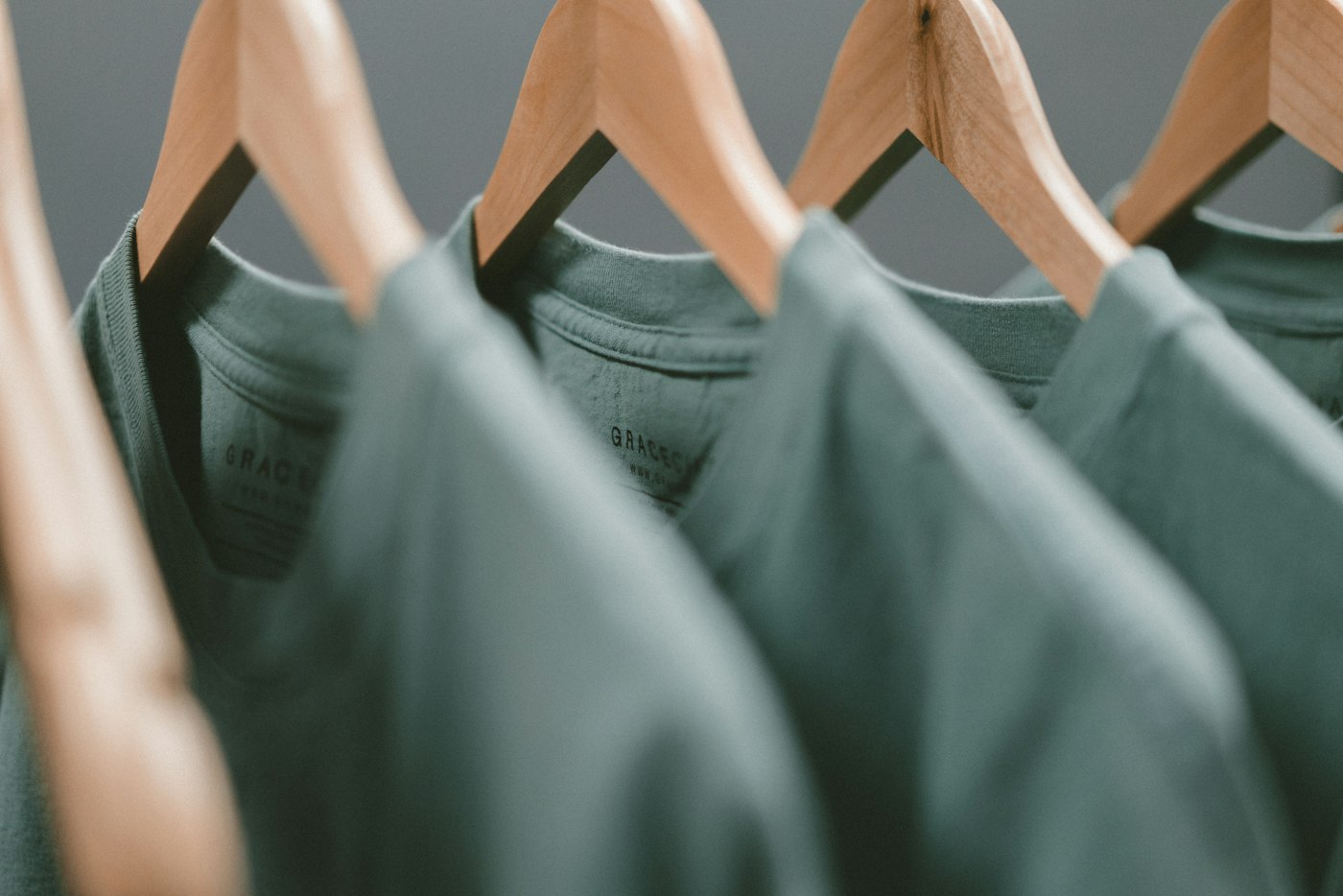 Green cotton shirts hanging on wooden hangers