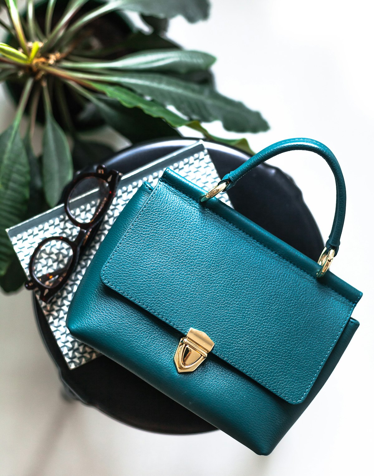 Teal leather top-handle bag with a gold clasp